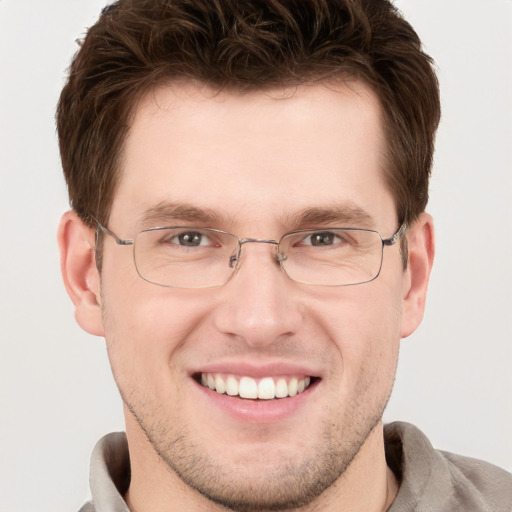 Joyful white young-adult male with short  brown hair and grey eyes