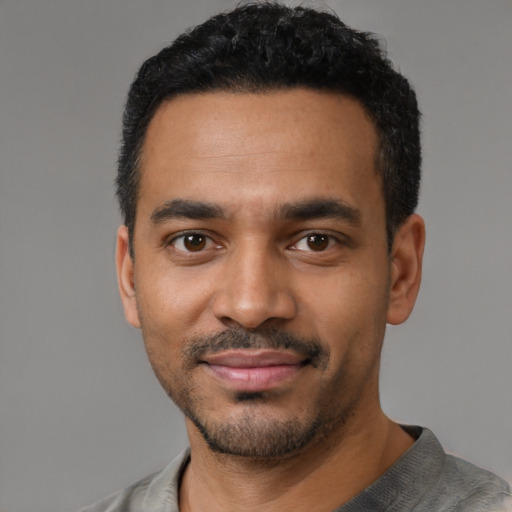 Joyful black young-adult male with short  black hair and brown eyes