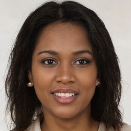 Joyful black young-adult female with long  brown hair and brown eyes