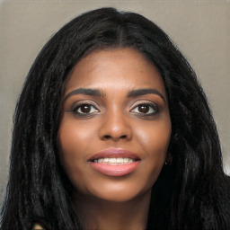 Joyful black young-adult female with long  black hair and brown eyes