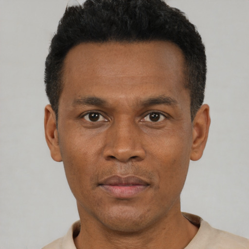Joyful black adult male with short  black hair and brown eyes