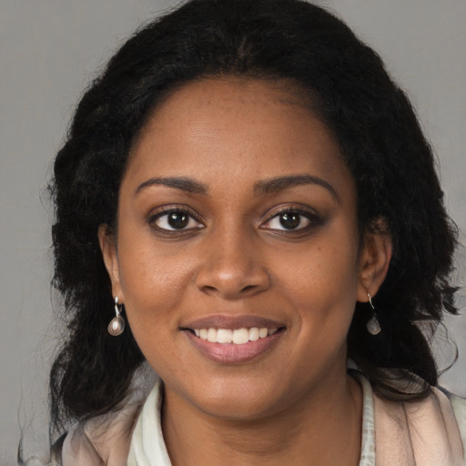 Joyful black young-adult female with long  brown hair and brown eyes