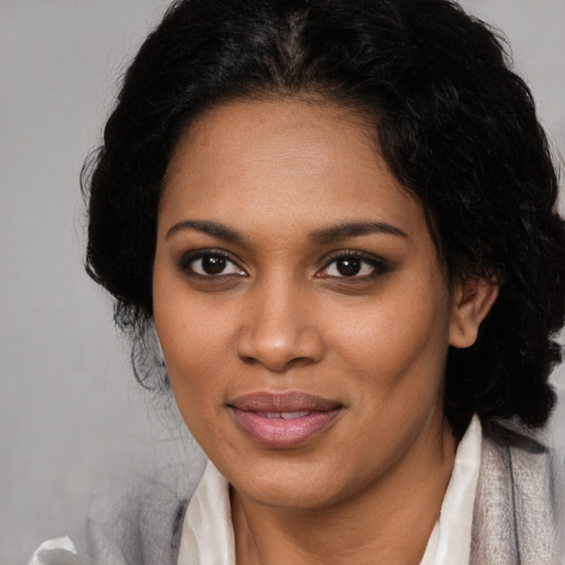 Joyful black young-adult female with long  black hair and brown eyes