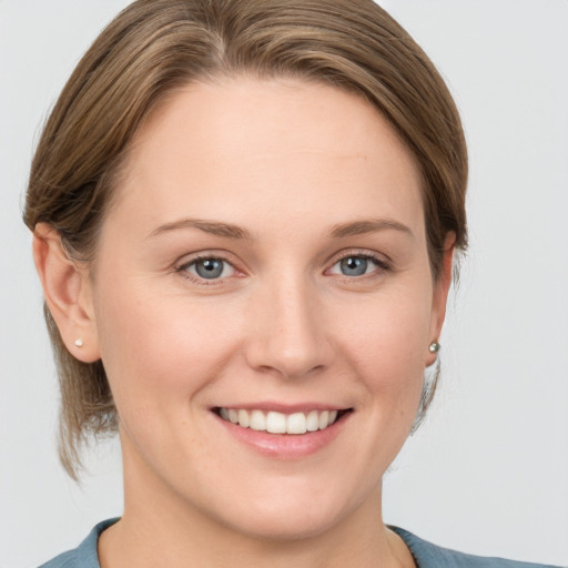 Joyful white young-adult female with medium  brown hair and grey eyes