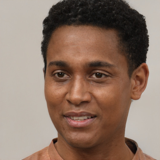 Joyful black young-adult male with short  black hair and brown eyes