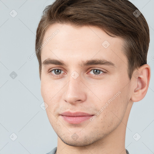 Joyful white young-adult male with short  brown hair and grey eyes