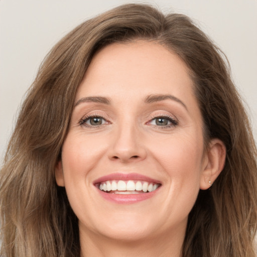 Joyful white adult female with long  brown hair and green eyes