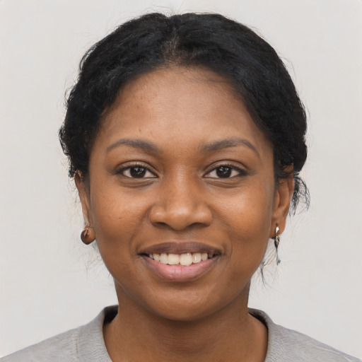 Joyful black young-adult female with short  black hair and brown eyes