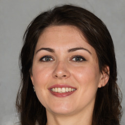 Joyful white young-adult female with long  brown hair and brown eyes