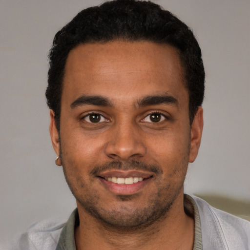 Joyful black young-adult male with short  brown hair and brown eyes