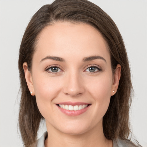 Joyful white young-adult female with medium  brown hair and grey eyes