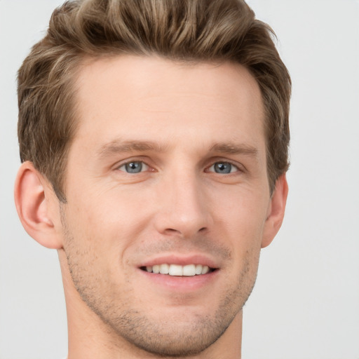 Joyful white young-adult male with short  brown hair and grey eyes