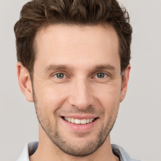 Joyful white young-adult male with short  brown hair and grey eyes