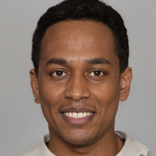 Joyful black young-adult male with short  black hair and brown eyes