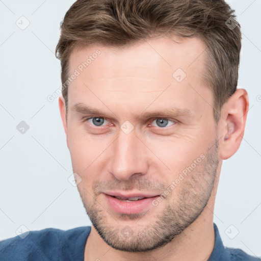 Joyful white young-adult male with short  brown hair and grey eyes