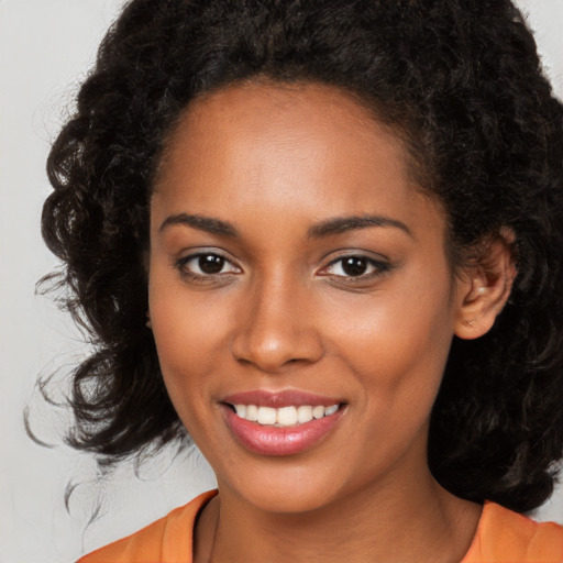 Joyful black young-adult female with long  brown hair and brown eyes