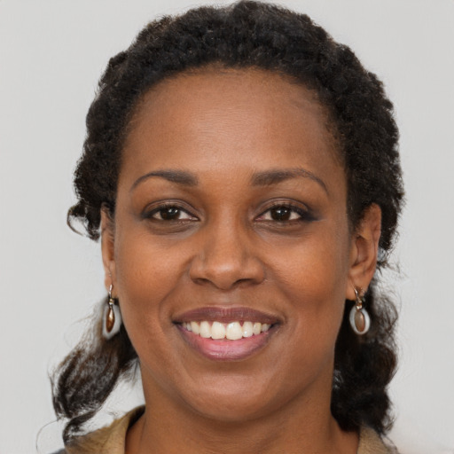 Joyful black adult female with long  brown hair and brown eyes