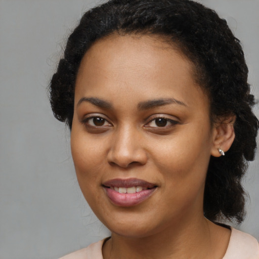 Joyful black young-adult female with long  brown hair and brown eyes