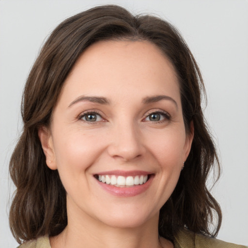 Joyful white young-adult female with medium  brown hair and grey eyes