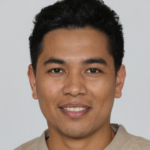 Joyful latino young-adult male with short  black hair and brown eyes