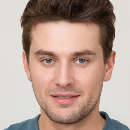 Joyful white young-adult male with short  brown hair and grey eyes