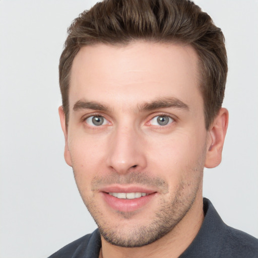 Joyful white young-adult male with short  brown hair and grey eyes