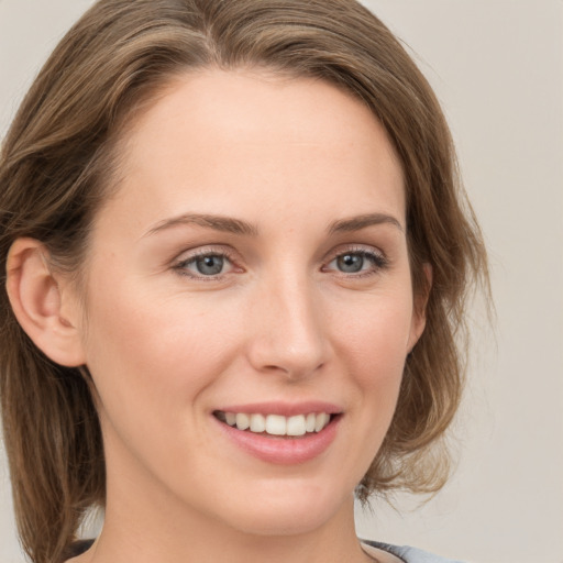 Joyful white young-adult female with medium  brown hair and grey eyes