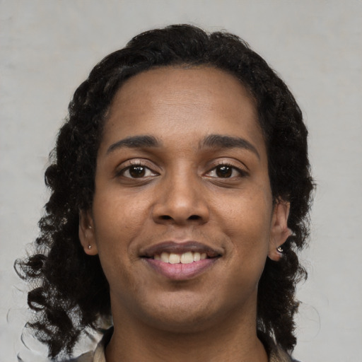 Joyful black young-adult female with long  black hair and brown eyes