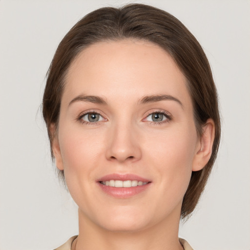 Joyful white young-adult female with medium  brown hair and grey eyes