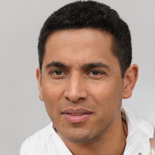 Joyful latino young-adult male with short  black hair and brown eyes