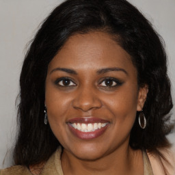 Joyful black young-adult female with long  brown hair and brown eyes