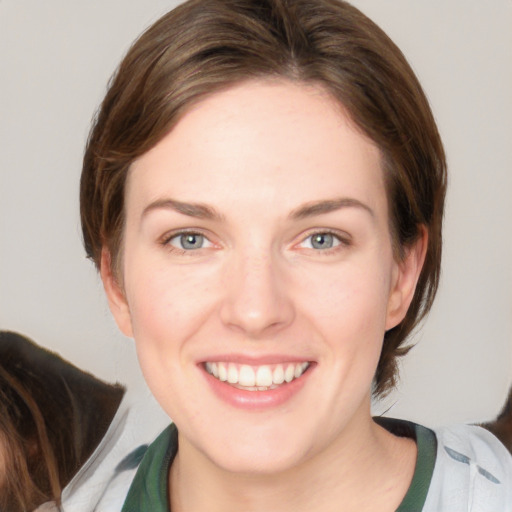 Joyful white young-adult female with medium  brown hair and grey eyes