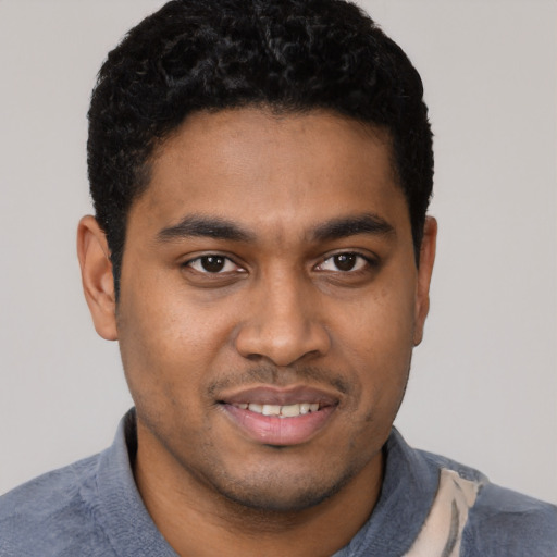 Joyful black young-adult male with short  black hair and brown eyes