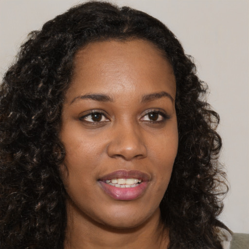 Joyful black young-adult female with long  brown hair and brown eyes