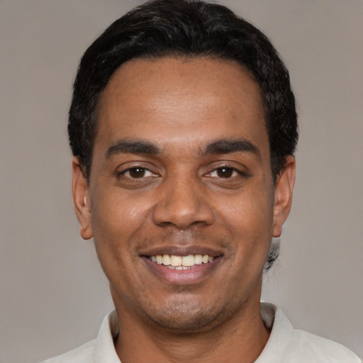 Joyful black young-adult male with short  black hair and brown eyes