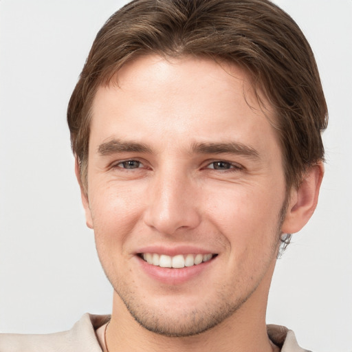 Joyful white young-adult male with short  brown hair and grey eyes