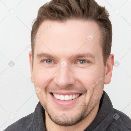 Joyful white young-adult male with short  brown hair and grey eyes