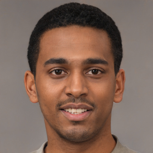 Joyful black young-adult male with short  black hair and brown eyes