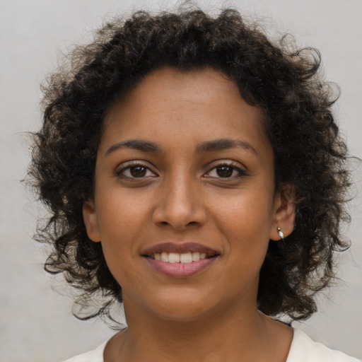 Joyful black young-adult female with short  brown hair and brown eyes