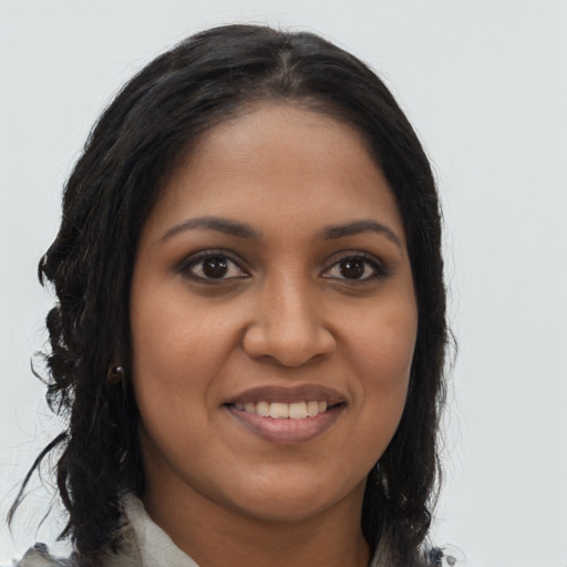 Joyful black young-adult female with long  brown hair and brown eyes