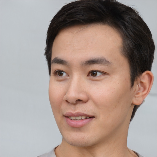 Joyful asian young-adult male with short  brown hair and brown eyes