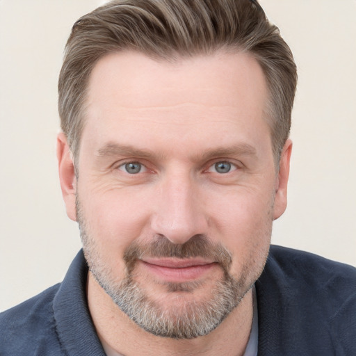 Joyful white adult male with short  brown hair and blue eyes