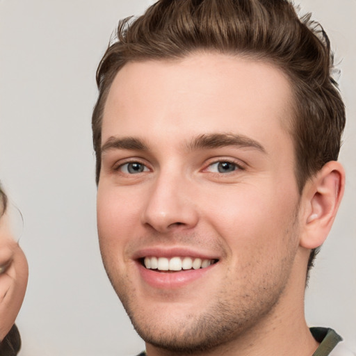 Joyful white young-adult male with short  brown hair and grey eyes