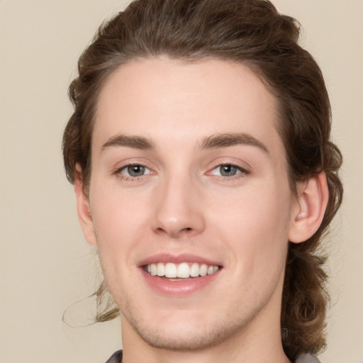 Joyful white young-adult male with medium  brown hair and grey eyes