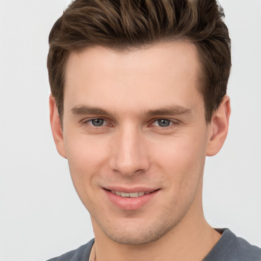 Joyful white young-adult male with short  brown hair and grey eyes