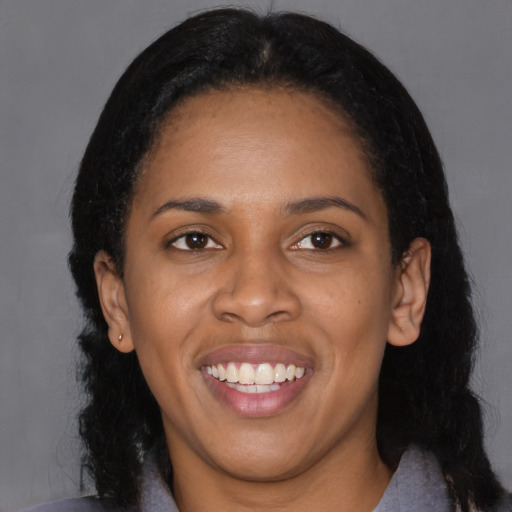 Joyful black young-adult female with long  black hair and brown eyes