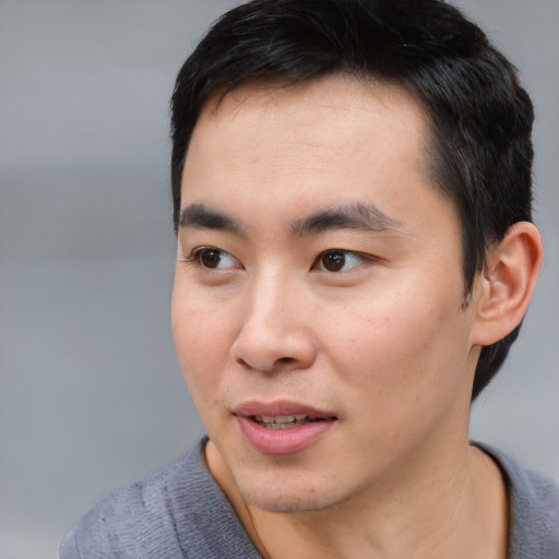 Joyful asian young-adult male with short  black hair and brown eyes