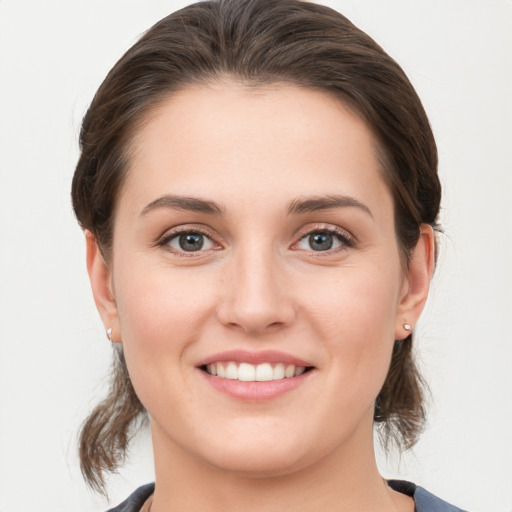 Joyful white young-adult female with medium  brown hair and grey eyes