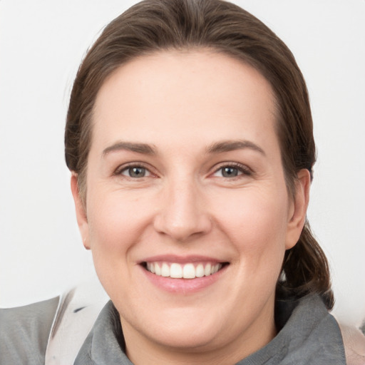 Joyful white young-adult female with medium  brown hair and grey eyes