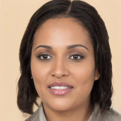 Joyful black young-adult female with long  brown hair and brown eyes